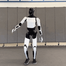 a black and white robot is dancing in front of a gray wall