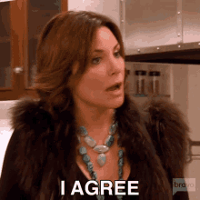 a woman wearing a fur coat and a turquoise necklace is saying `` i agree '' .