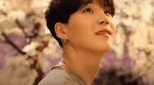 a close up of a person 's face with flowers in the background and looking up .