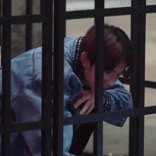 a person behind bars with a hand on their forehead