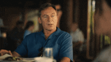 a man in a blue shirt is sitting at a table