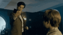 a man in a suit is pointing at a boy in a white shirt