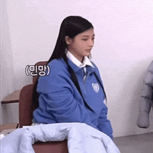 a woman in a blue jacket sits in a chair