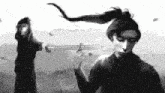 a black and white photo of a man holding a sword in front of a woman .