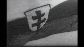 a black and white photo of a flag with a shield with a cross on it
