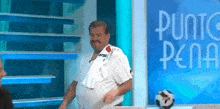 a man with a towel around his neck is standing in front of a blue sign that says punto pena