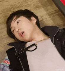 a young man is laying on a wooden floor wearing glasses and a jacket .