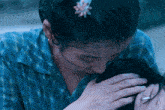 a woman with a flower in her hair is touching another woman 's head