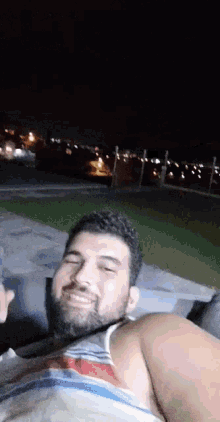 a man with a beard is laying on a couch at night .