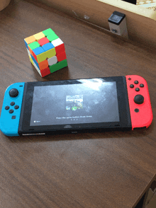 a nintendo switch is sitting on a wooden table next to a rubik 's cube