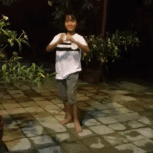 a little girl is standing on a tiled floor with her arms outstretched