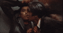 a man is holding another man 's face with blood on it
