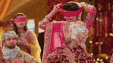 a woman in a pink dress is dancing with a man in a turban .