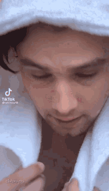 a man is wrapped in a white towel and looking down at something .