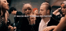 a group of people are standing in a room with the words `` it was so nice throwing big parties '' above them .
