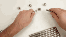 a person is playing with a bunch of metal balls on a table