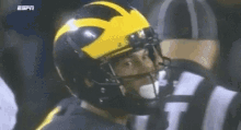 a football player wearing a yellow helmet with the letter m on it