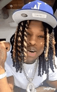 a man with dreadlocks wearing a blue hat and a necklace .