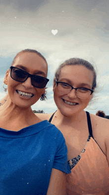 two women wearing sunglasses and braces pose for a photo