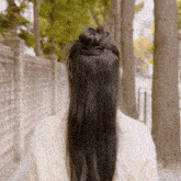 a woman with long hair is wearing a white sweater and has her hair in a bun