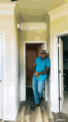 a man in a blue shirt is leaning against a wall in a hallway