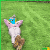 a picture of a person laying on the grass with a cartoon character on their head