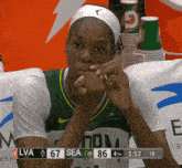a female basketball player sitting in front of a scoreboard that says lva 67 sea 86 4th 18