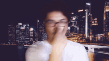 a blurry picture of a man covering his face with his hand in front of a city skyline
