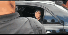 a man is standing next to a woman in a car looking out the window .