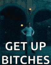 a man in a white shirt is dancing in front of a sign that says get up bitches .