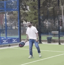 a man is holding a tennis racquet on a tennis court with mizuno advertisements on the wall behind him