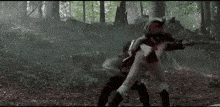 a man is fighting another man with a sword in a forest .