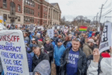 a large crowd of people are holding signs and walking down a street .