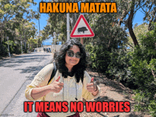 a woman stands in front of a sign that says hakuna matata