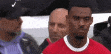 a man in a red shirt is standing next to a man in a black hat .