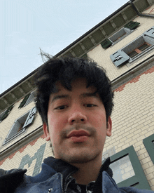a man taking a selfie in front of a brick building with the letter f on it
