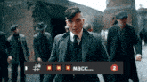 a man in a suit and tie is standing in front of a sign that says macc