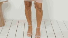 a woman in a pink dress is standing in front of a white wall and looking at the camera .