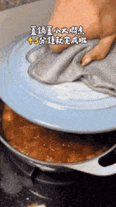 a person is holding a towel over a pot with chinese writing