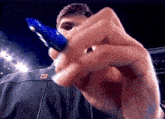 a man holding a blue pen with the letter e on his jacket