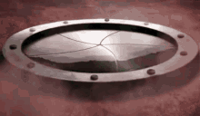 a metal circle with a hole in the middle of it is sitting on a red surface .