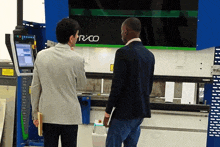 two men are looking at a machine that says rico