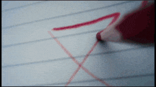 a red pencil is drawing the letter x on a sheet of paper