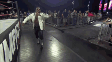 a man in a white jacket is walking in front of a wrestling ring that says npw