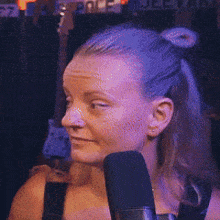 a woman is sitting in front of a microphone with a ponytail
