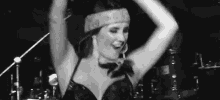 a woman in a bandana is dancing on a stage in a black and white photo .