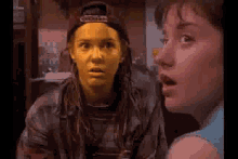 a woman with yellow paint on her face is standing next to another woman with a surprised look on her face .