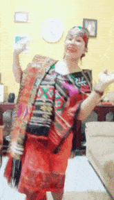 a woman in a red dress and headband is dancing in a living room