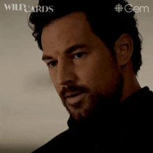 a close up of a man 's face with wildcards and gem logos behind him