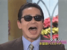 a man in a suit and tie wearing sunglasses with his mouth open .